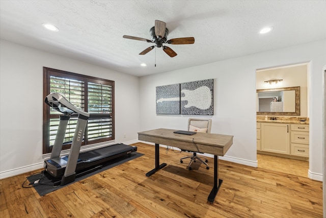 exercise area featuring ceiling fan, a textured ceiling, and light hardwood / wood-style flooring