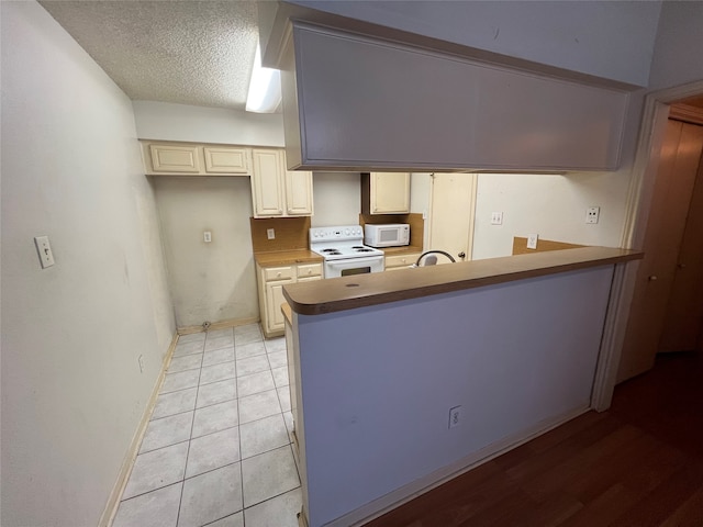 kitchen with cream cabinets, white appliances, light hardwood / wood-style floors, sink, and a textured ceiling