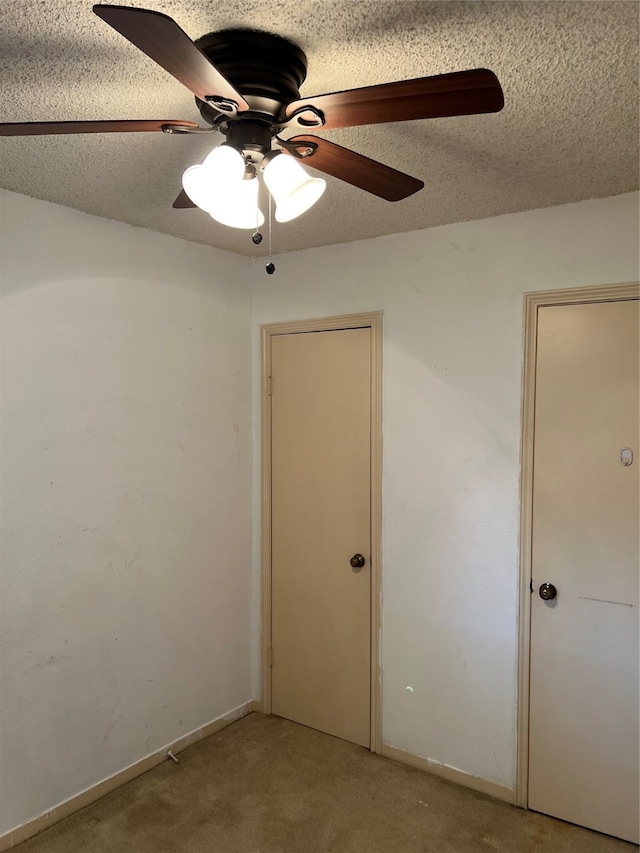 unfurnished bedroom featuring light carpet, a textured ceiling, and ceiling fan