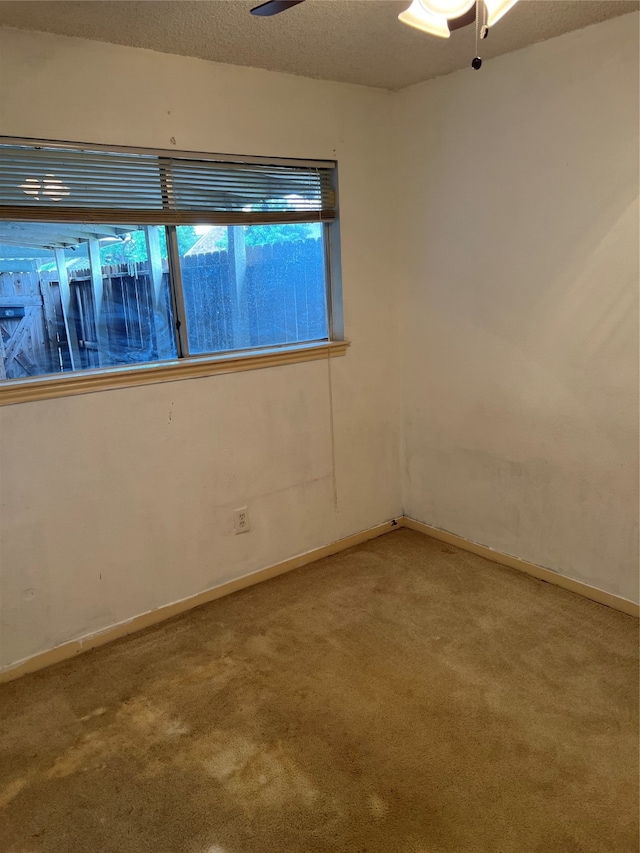 carpeted empty room featuring ceiling fan and a textured ceiling