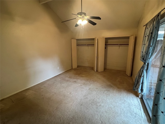 unfurnished bedroom featuring lofted ceiling, carpet, multiple closets, and ceiling fan