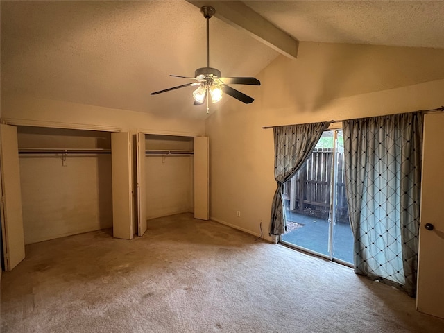 unfurnished bedroom featuring carpet floors, access to outside, multiple closets, ceiling fan, and vaulted ceiling with beams