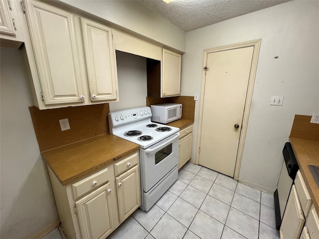 kitchen featuring cream cabinets, white appliances, light tile patterned floors, and a textured ceiling