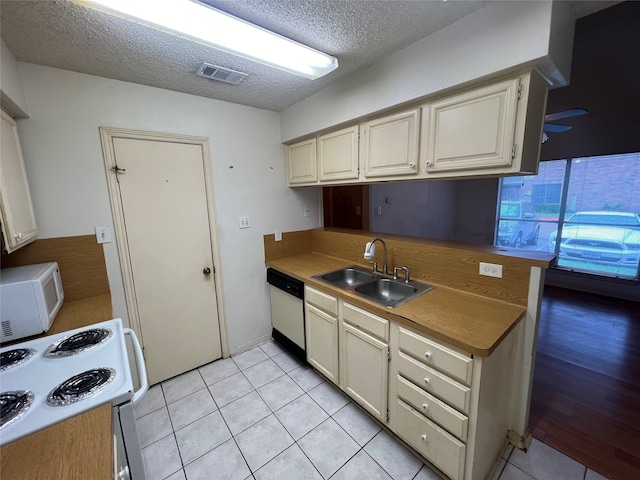 kitchen featuring a textured ceiling, white appliances, sink, cream cabinets, and light hardwood / wood-style floors