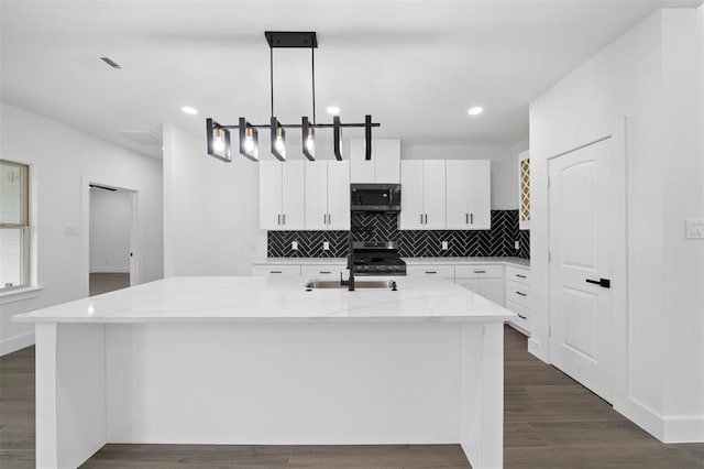 kitchen featuring hanging light fixtures, stainless steel appliances, dark hardwood / wood-style flooring, white cabinetry, and a kitchen island with sink