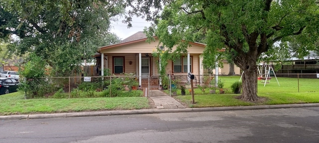 bungalow-style home with a playground, a front yard, and covered porch