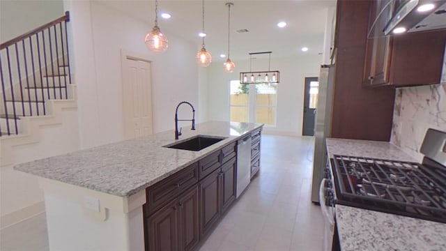 kitchen featuring light stone counters, stainless steel appliances, extractor fan, sink, and a center island with sink