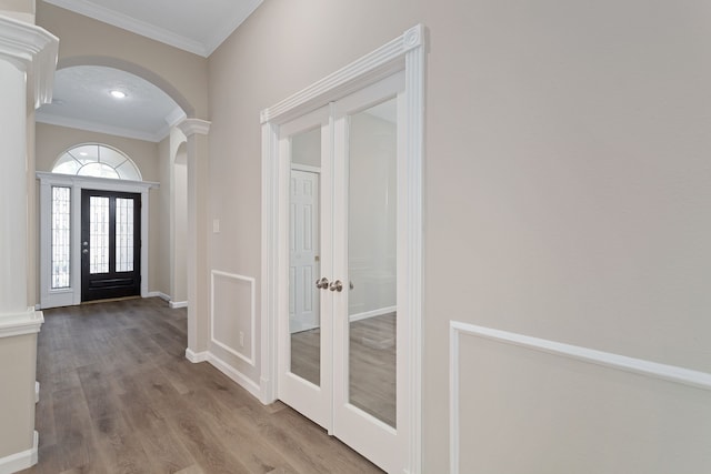 entryway with hardwood / wood-style floors, ornamental molding, and french doors