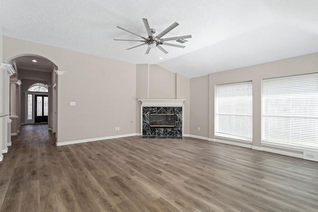 unfurnished living room with a fireplace, dark hardwood / wood-style flooring, lofted ceiling, ceiling fan, and a textured ceiling