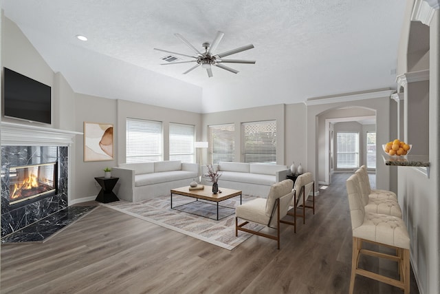 living room featuring a premium fireplace, ceiling fan, a healthy amount of sunlight, and dark wood-type flooring