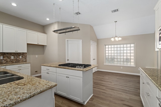 kitchen featuring dark wood-type flooring, white cabinets, stainless steel gas cooktop, and vaulted ceiling