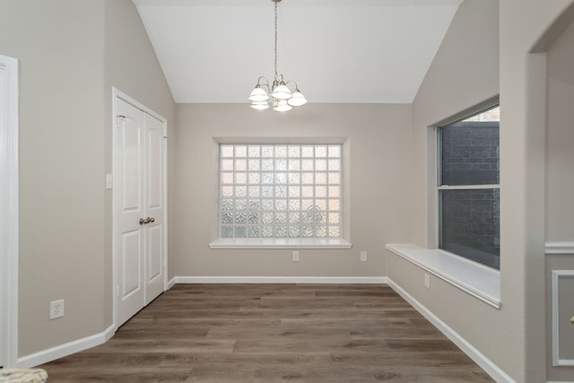 unfurnished dining area featuring dark wood-type flooring, vaulted ceiling, a healthy amount of sunlight, and a chandelier