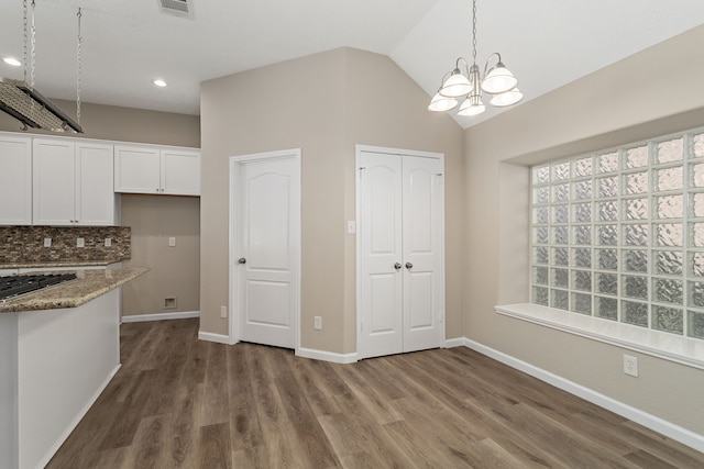 kitchen with white cabinets, stone counters, dark hardwood / wood-style flooring, lofted ceiling, and pendant lighting