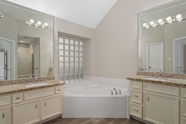 bathroom featuring vanity, vaulted ceiling, plus walk in shower, and hardwood / wood-style floors