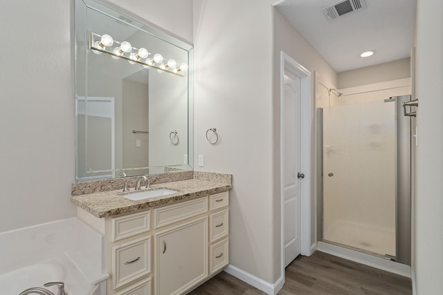 bathroom featuring vanity, wood-type flooring, and plus walk in shower