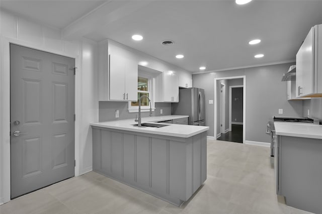 kitchen with light countertops, appliances with stainless steel finishes, a peninsula, and a sink