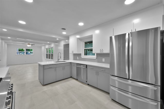 kitchen with open floor plan, gray cabinets, stainless steel appliances, light countertops, and a sink