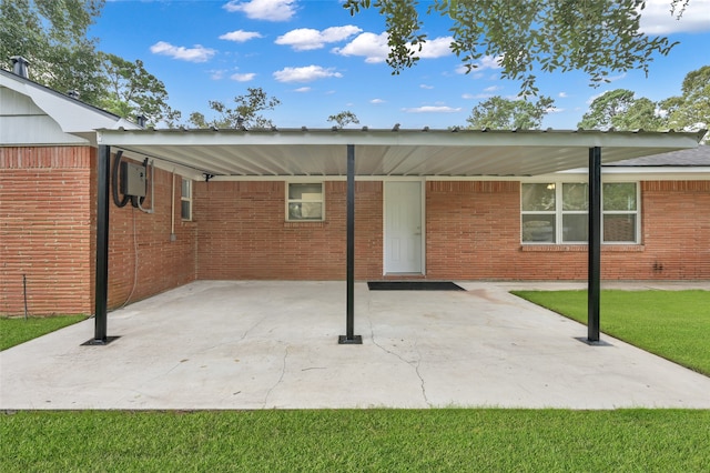 rear view of property featuring a carport, brick siding, and a yard