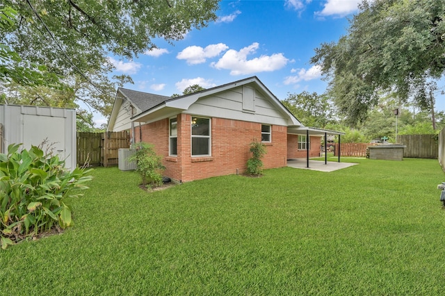 back of house featuring brick siding, a fenced backyard, a yard, and a patio