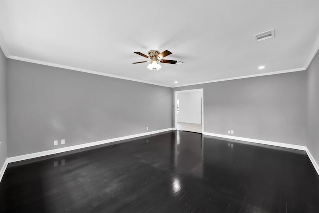 empty room with baseboards, visible vents, crown molding, and wood finished floors