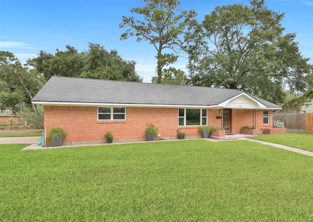 single story home featuring brick siding, fence, and a front yard