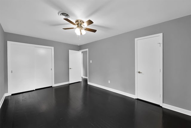 unfurnished bedroom featuring baseboards, visible vents, dark wood finished floors, ceiling fan, and a closet