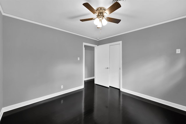 unfurnished room with ornamental molding, ceiling fan, baseboards, and dark wood-style floors