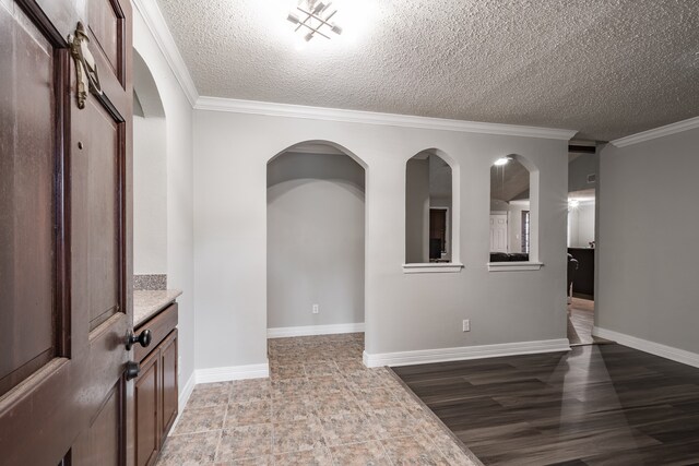 interior space with a textured ceiling, crown molding, and hardwood / wood-style flooring