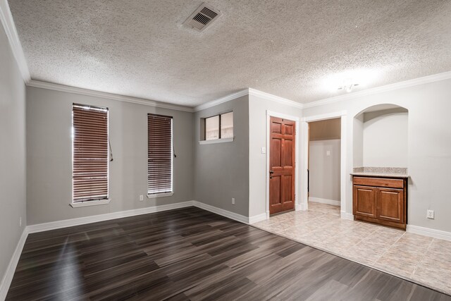 unfurnished room with crown molding, a textured ceiling, and dark hardwood / wood-style floors