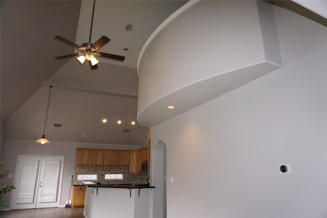 interior space with high vaulted ceiling, kitchen peninsula, ceiling fan, and wood-type flooring