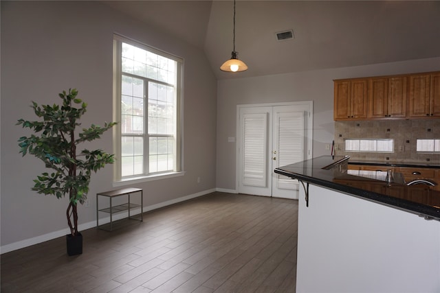 kitchen featuring decorative light fixtures, dark hardwood / wood-style floors, vaulted ceiling, and decorative backsplash