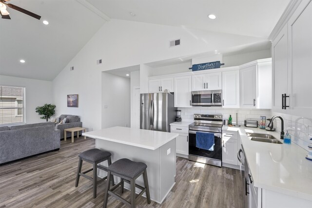 kitchen with light hardwood / wood-style flooring, a center island, stainless steel appliances, sink, and white cabinets