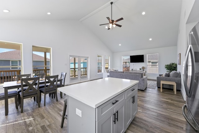 kitchen featuring stainless steel fridge, a center island, dark wood-type flooring, high vaulted ceiling, and ceiling fan