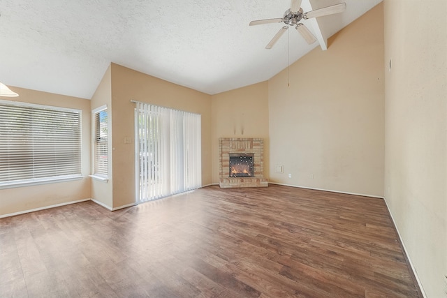 unfurnished living room featuring dark hardwood / wood-style flooring, lofted ceiling, a brick fireplace, and ceiling fan