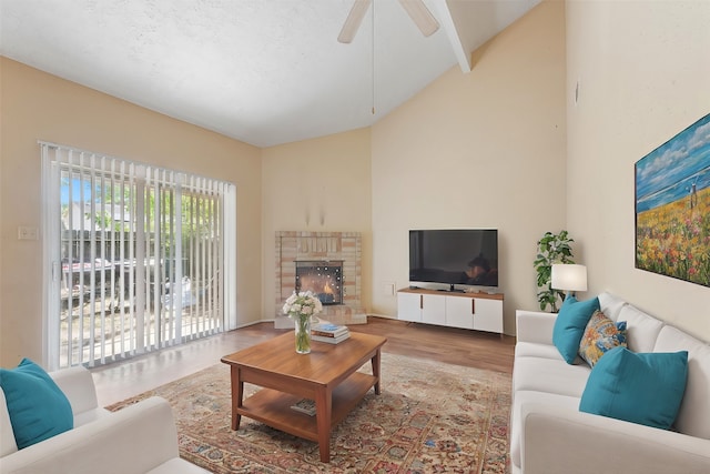 living room with ceiling fan, hardwood / wood-style floors, high vaulted ceiling, and a fireplace