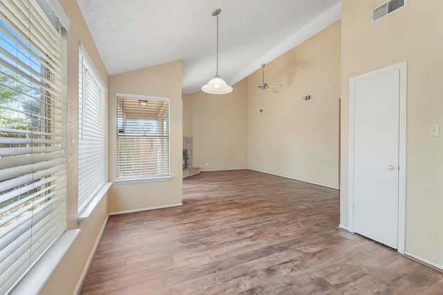 spare room with lofted ceiling, plenty of natural light, ceiling fan, and wood-type flooring