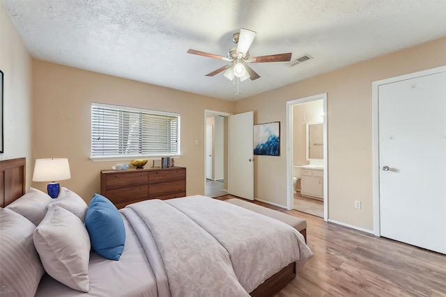 bedroom featuring light wood-type flooring, ceiling fan, and connected bathroom