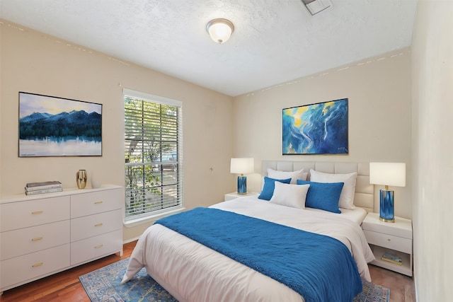 bedroom with a textured ceiling and wood-type flooring