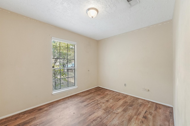 empty room with a textured ceiling and hardwood / wood-style flooring