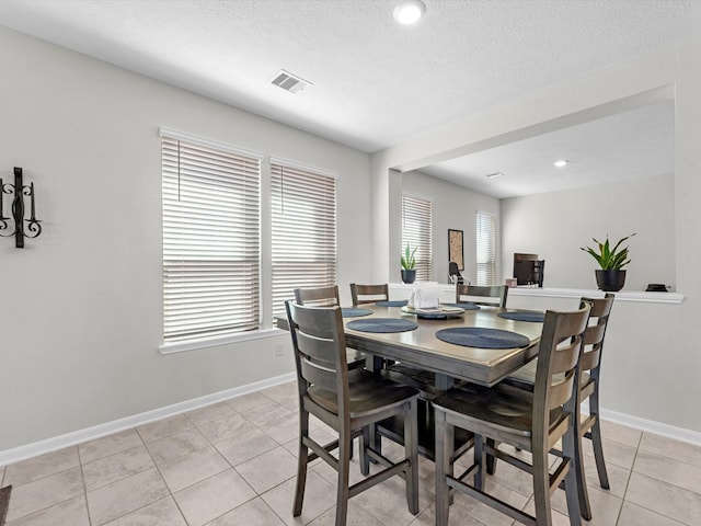 tiled dining room with a wealth of natural light and a textured ceiling