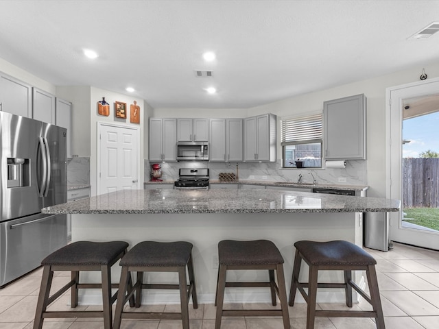 kitchen with dark stone countertops, a kitchen island, stainless steel appliances, and a kitchen breakfast bar