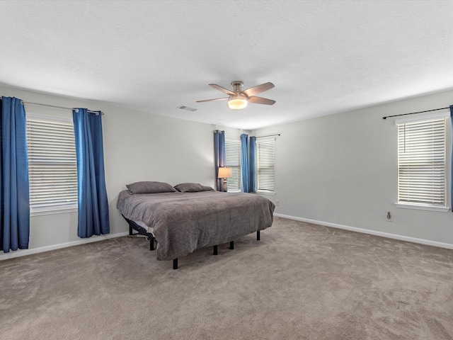 bedroom with ceiling fan, light colored carpet, and a textured ceiling