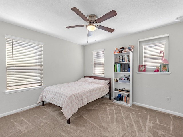 carpeted bedroom featuring a textured ceiling, ceiling fan, and multiple windows