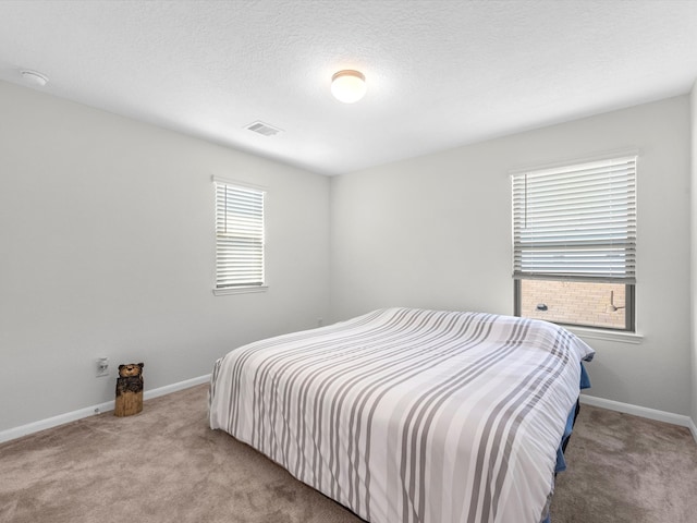 bedroom with light colored carpet and a textured ceiling