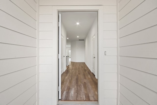 hall featuring dark wood-type flooring and wood walls