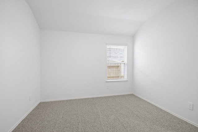 empty room featuring vaulted ceiling and carpet