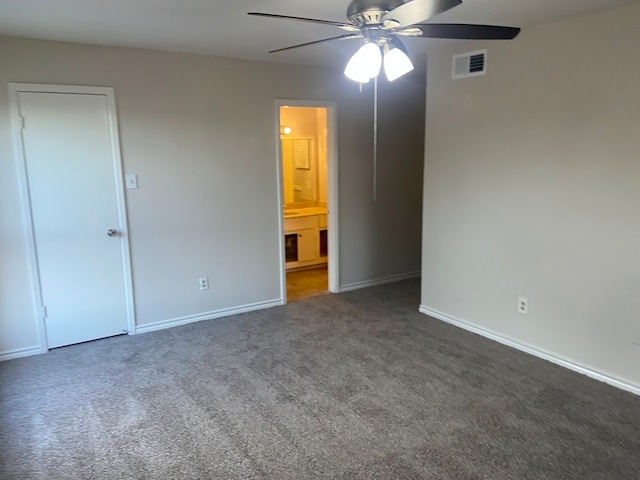 unfurnished bedroom with connected bathroom, dark carpet, and ceiling fan