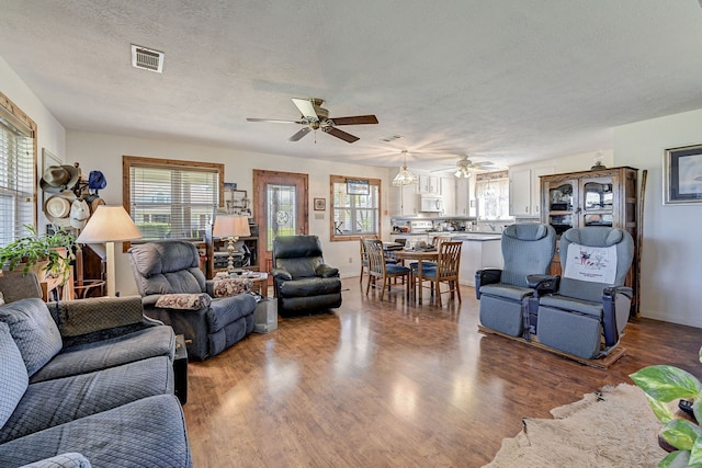 living room featuring ceiling fan, hardwood / wood-style flooring, and a textured ceiling