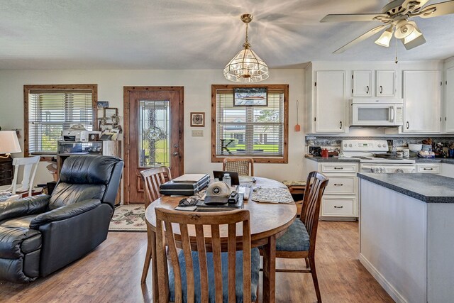 dining space featuring light wood-type flooring and ceiling fan with notable chandelier