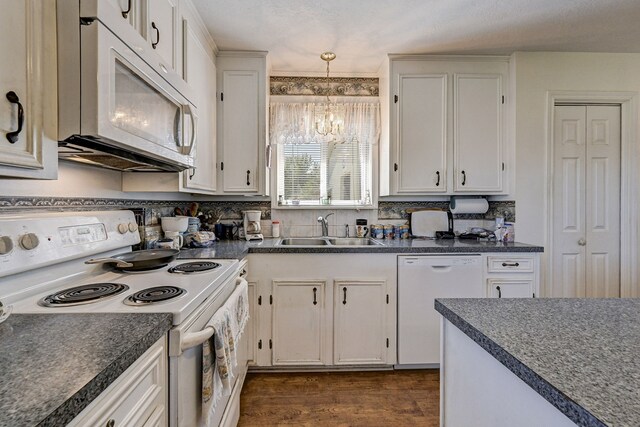 kitchen with white cabinetry, white appliances, an inviting chandelier, sink, and hanging light fixtures